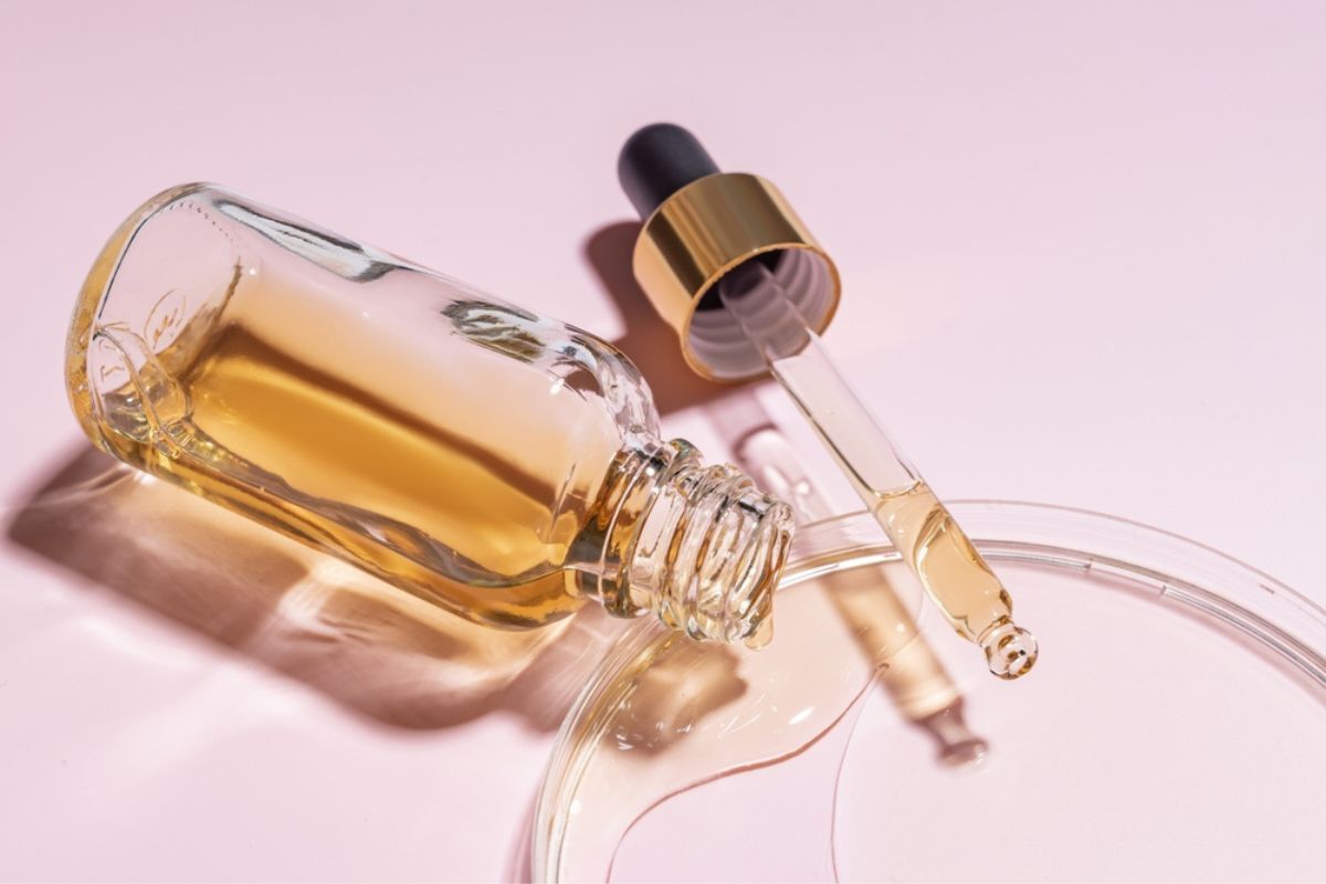 bao bì mỹ phẩm từ thuỷ tinh chai serum mở nắp nằm ngang chứa dung dịch màu vàng