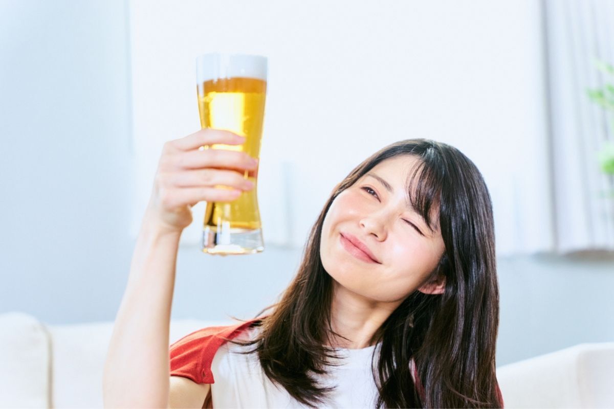 gội đầu bằng bia người phụ nữ mỉm cười ngồi trong phòng của cô ấy và nhìn vào ly bia