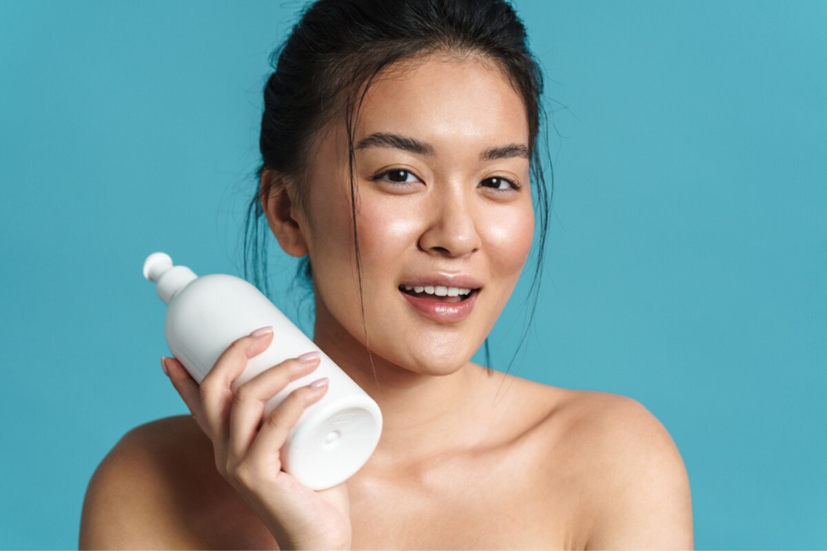 cách trị gàu mảng cô gái cầm trên tay chai dầu gội trị gàu mảng