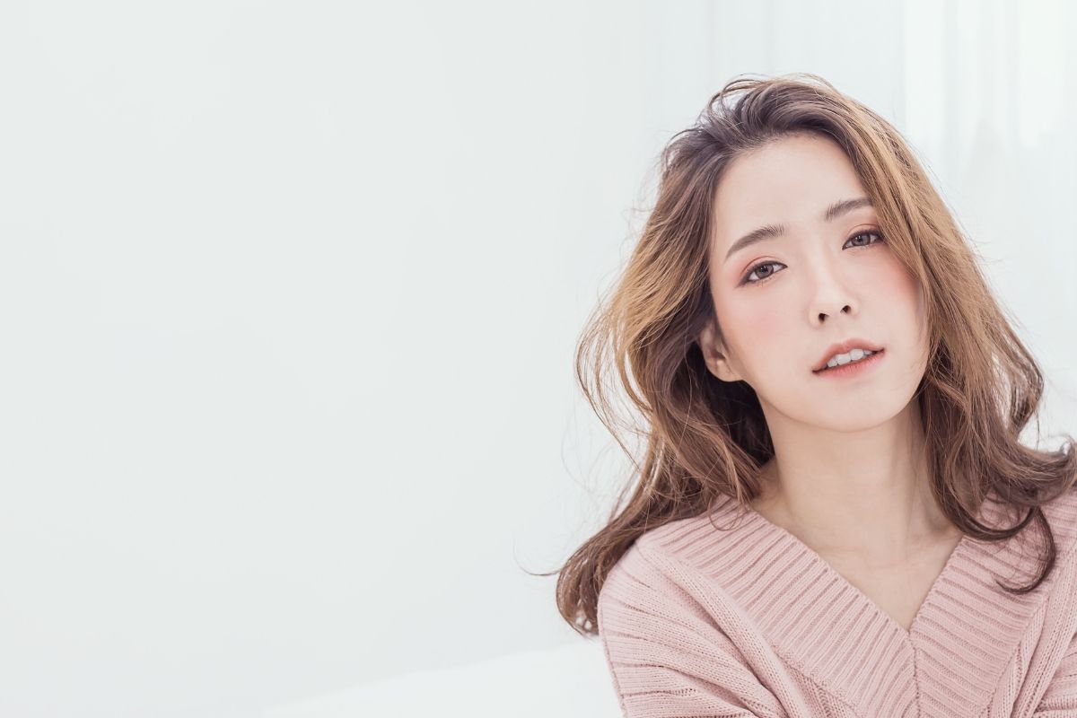 tóc màu nâu tây vàng cô gái tóc uốn lọn ngang vai mâc áo len cổ tim màu hồng nhạt