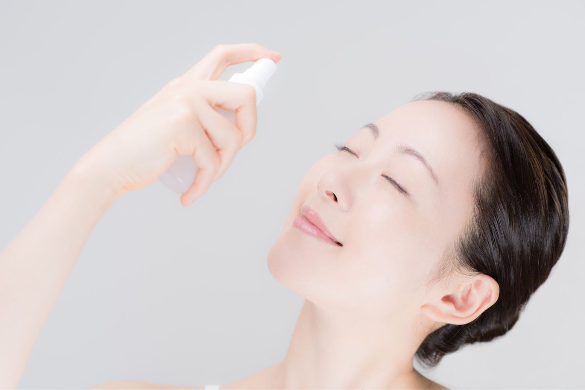  xịt khoáng có tác dụng gì cô gái nhắm mắt ngửa cười mỉm đang dùng xịt khoáng