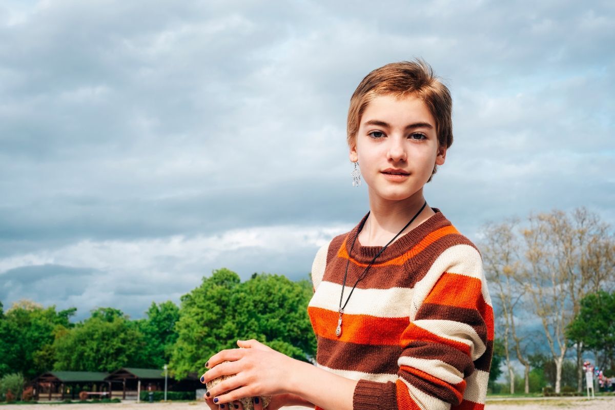 tóc ngắn mái thưa cho mặt dài và gầy, cô gái mặc áo sọc ngang màu đỏ 