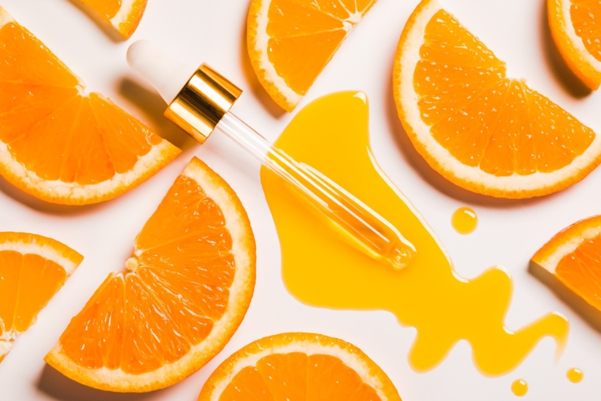 vitamin c có tác dụng gì với da mặt ống serum màu cam nằm giữa các lát cam trên nền trắng