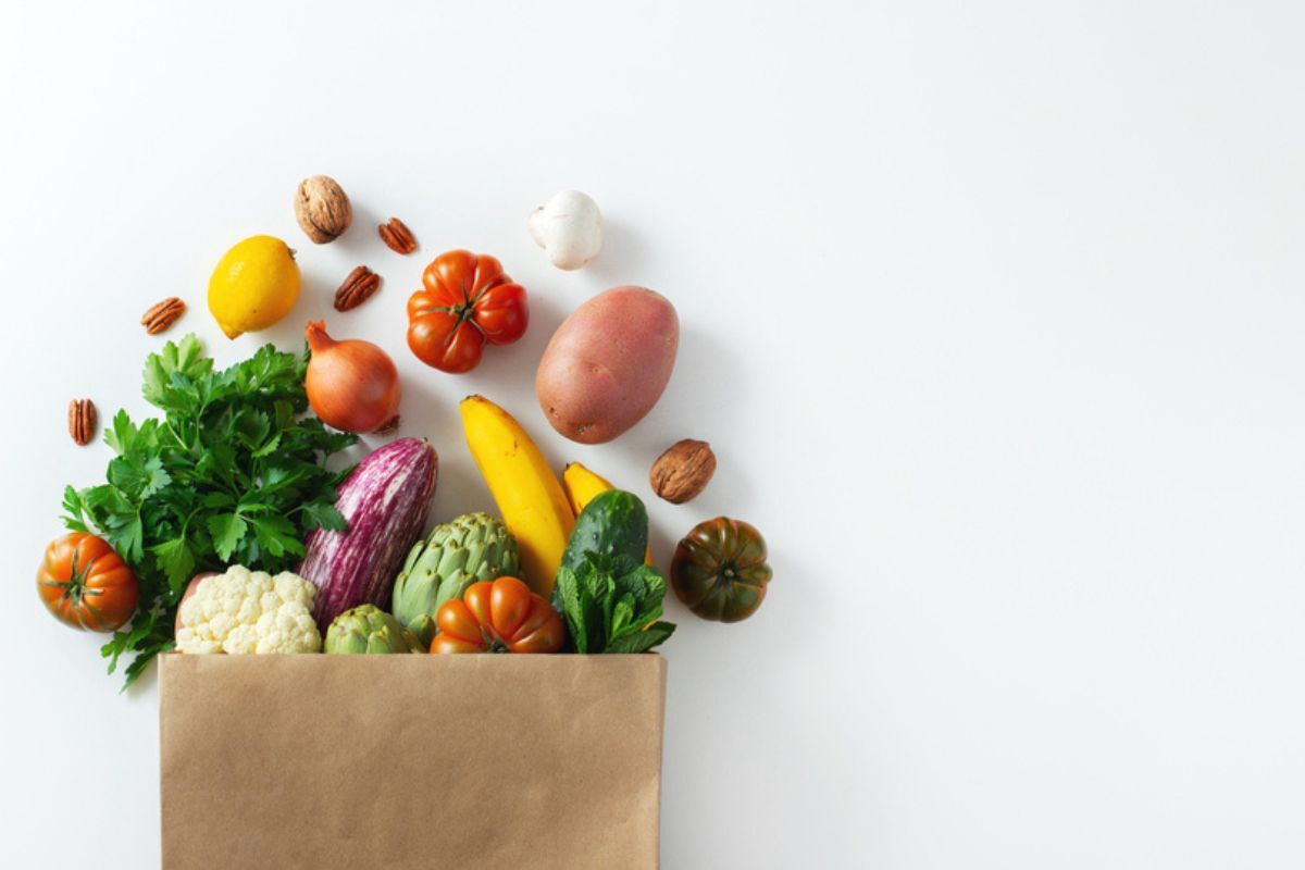 ăn gì để hết mụn giỏ giấy đựng thực phẩm cà chua hoa atiso hành tây chuối rau ngò quả óc chó trên nền trắngăn gì để hết mụn giỏ giấy đựng thực phẩm cà chua hoa atiso hành tây chuối rau ngò quả óc chó trên nền trắng