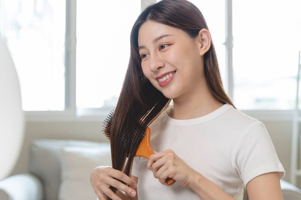 da đầu dầu cô gái cười tươi đang soi gương và chải tóc