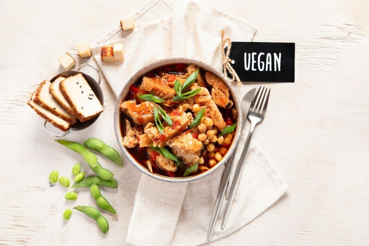 lợi ích của việc ăn chay chủ nghĩa thuần chay là gì món ăn được chế biến từ đậu hũ kế bên chén đựng đậu hũ và đậu hà lan có tấm bìa ghi chữ vegan