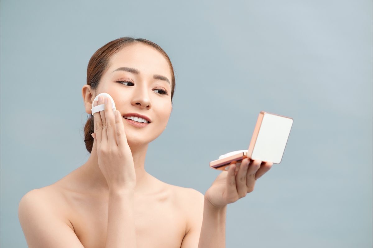 có nên sử dụng phấn nước cô gái búi tóc thấp đánh phấn nước trên nền xám