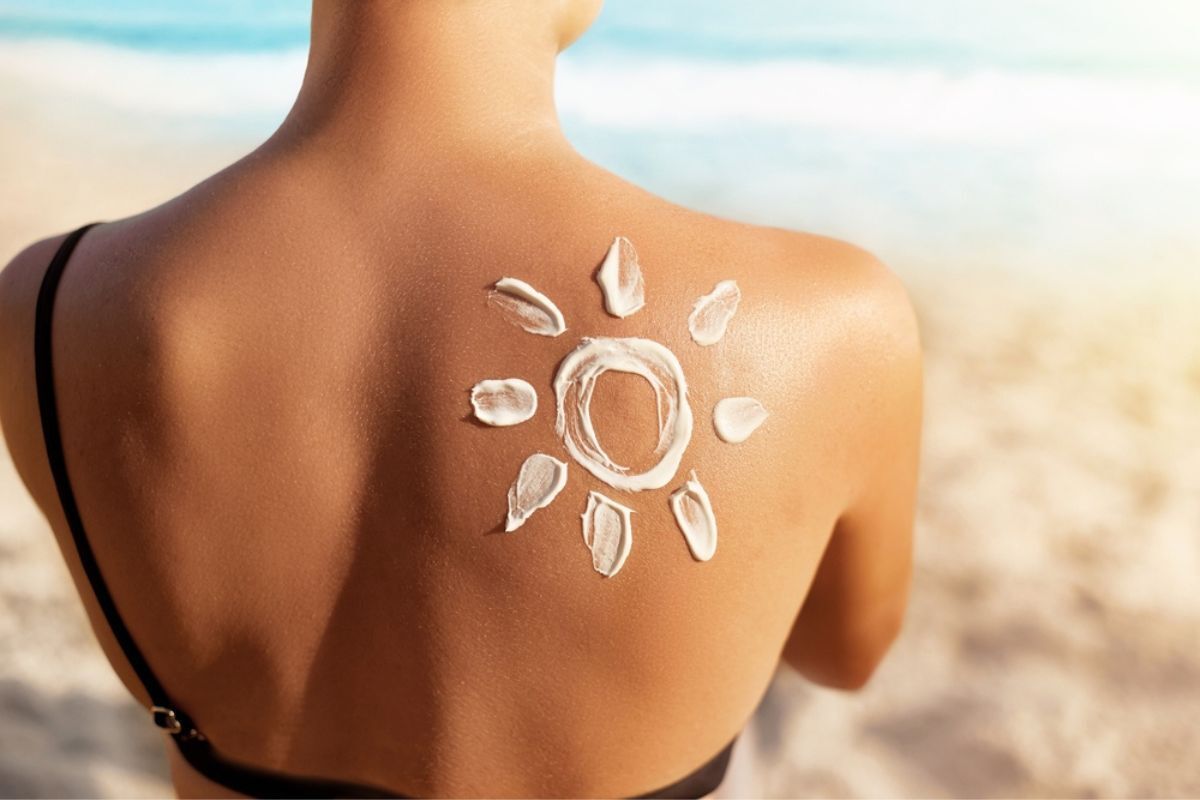 tắm nắng cô mặc đồ tắm đứng quay lưng với hình mặt trời vẻ bằng kem chống nắng