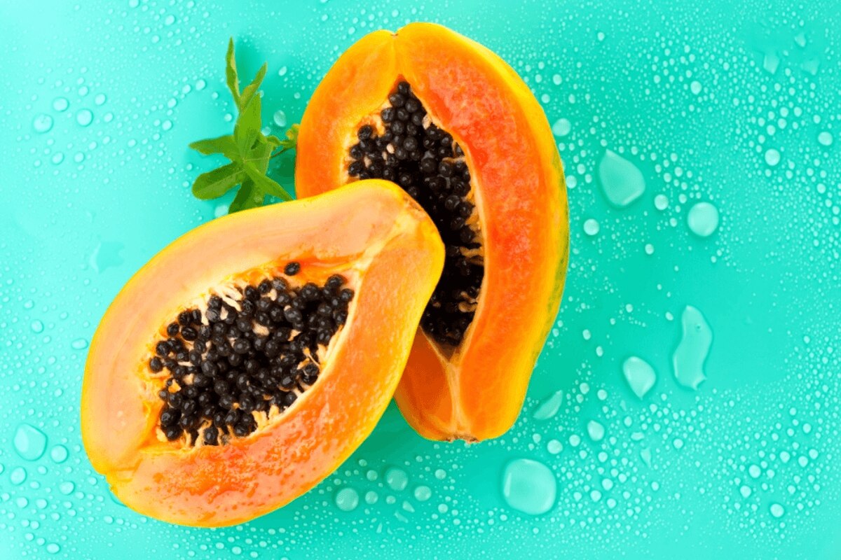 cách tẩy da chết tại nhà bằng đu đủ và đường quả đu đủ trên nền màu xanh với những giọt nước bắn xung quanh