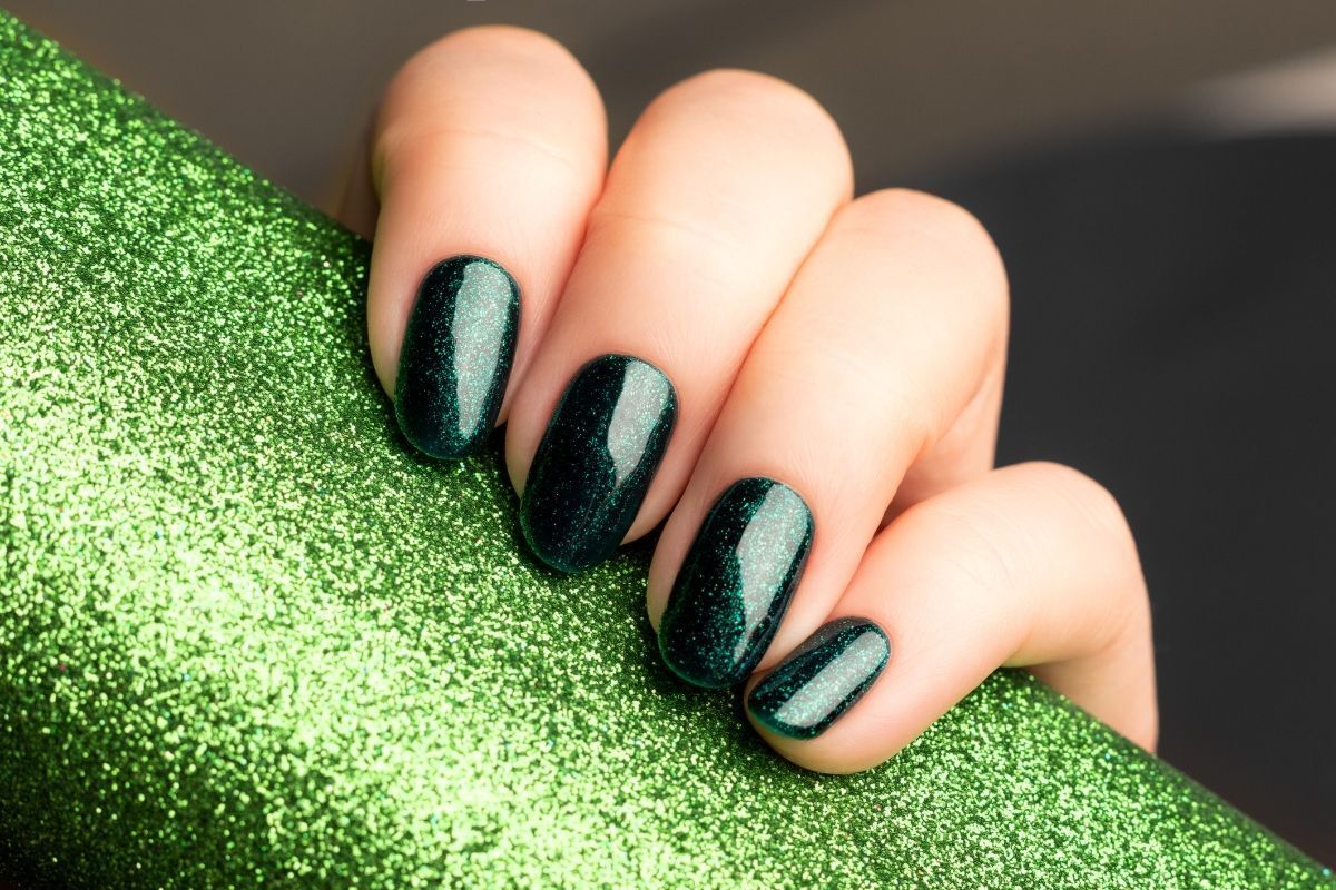 Nail màu xanh rêu đậm bàn tay cầm miếng giấy phủ kim tuyến màu xanh lá