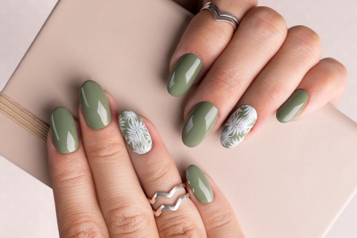 Mẫu nail đẹp màu xanh rêu có hoạ tiết màu trắng bàn tay đeo nhẫn ngón áp út