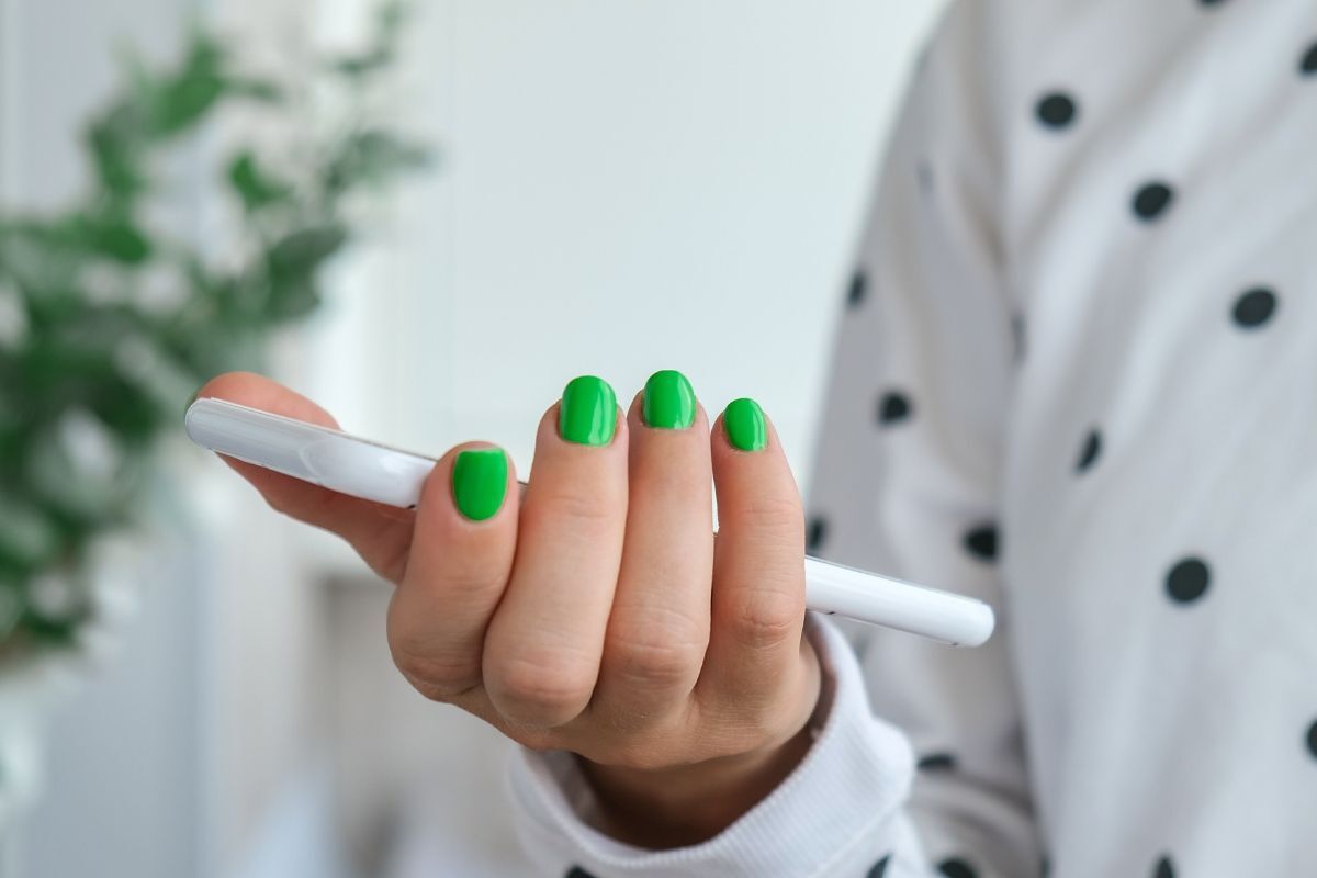 nail màu xanh lá cô gái móng tay màu xanh lá trơn cầm điện thoại mặc áo trắng chấm bi đen