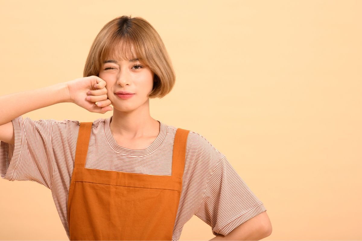 Mặt tròn nên để mái gì dễ thương cô gái mặc áo thun kẻ ngang đang để một tay lên má 