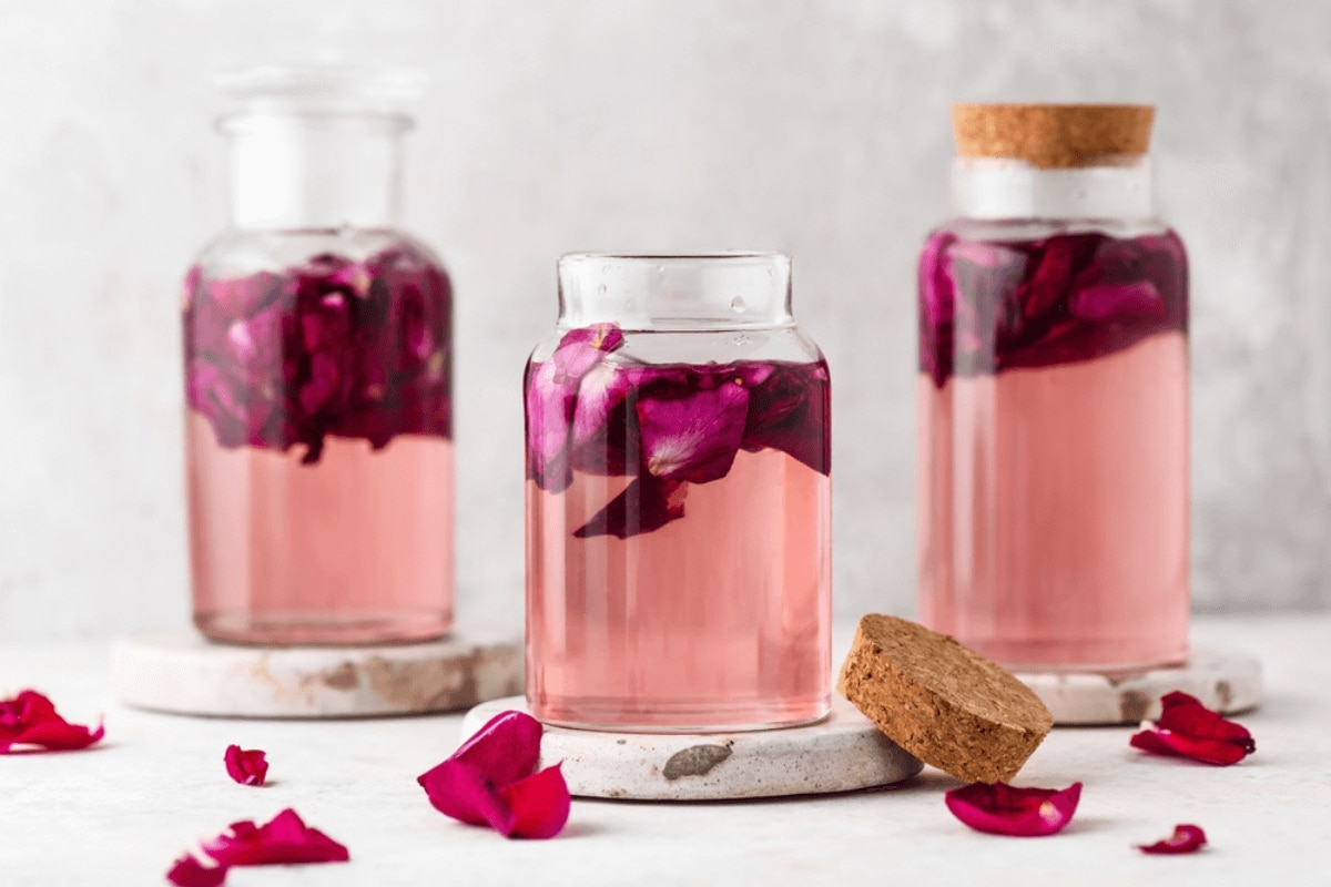 nước hoa hồng có tác dụng gì nguồn gốc của hoa hồng nước hoa hồng đựng trong chai thủy tinh có cánh hoa màu hồng bên trong