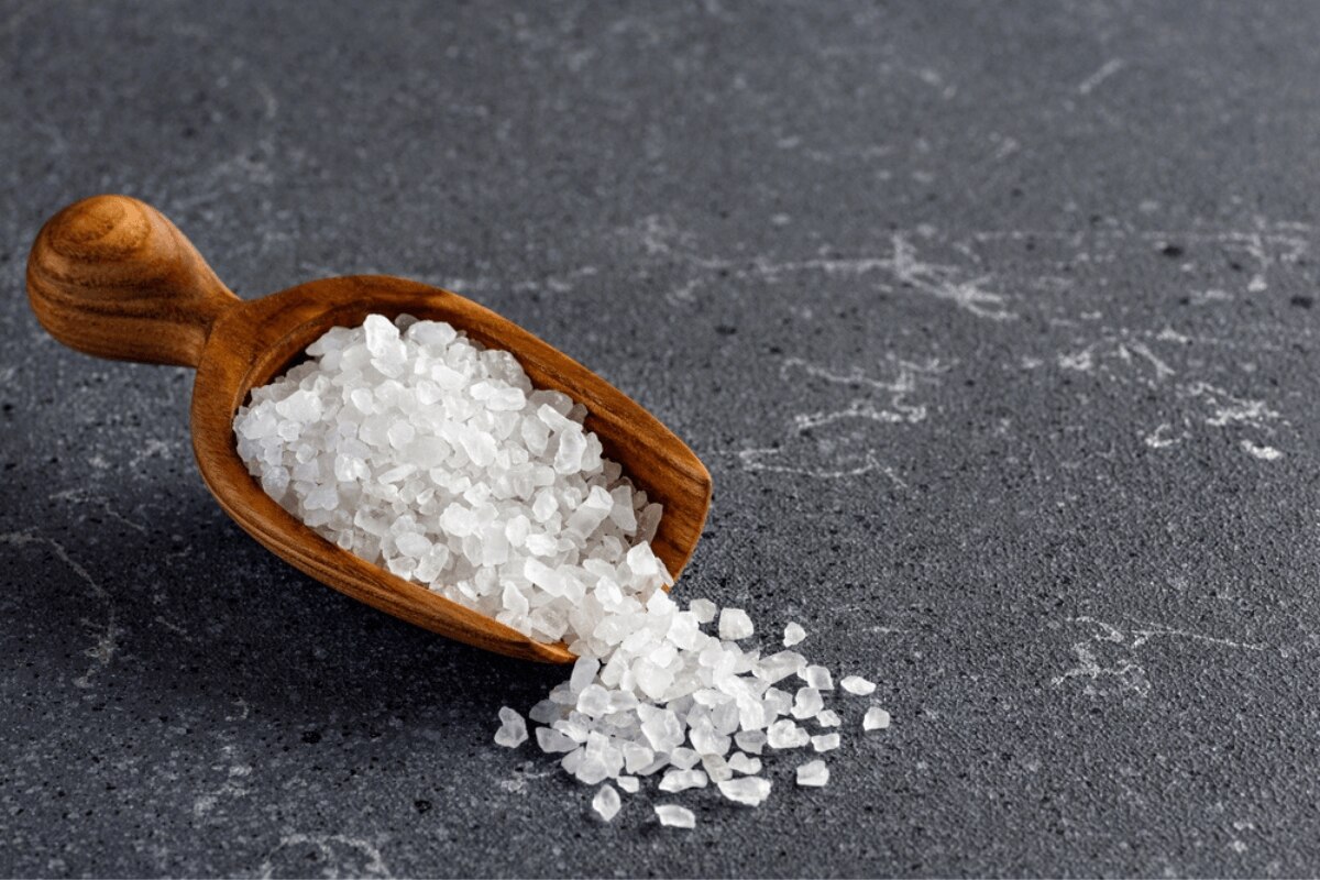 Cách trị mụn lưng tinh thể muối biển trong muỗng gỗ trên nền màu xám