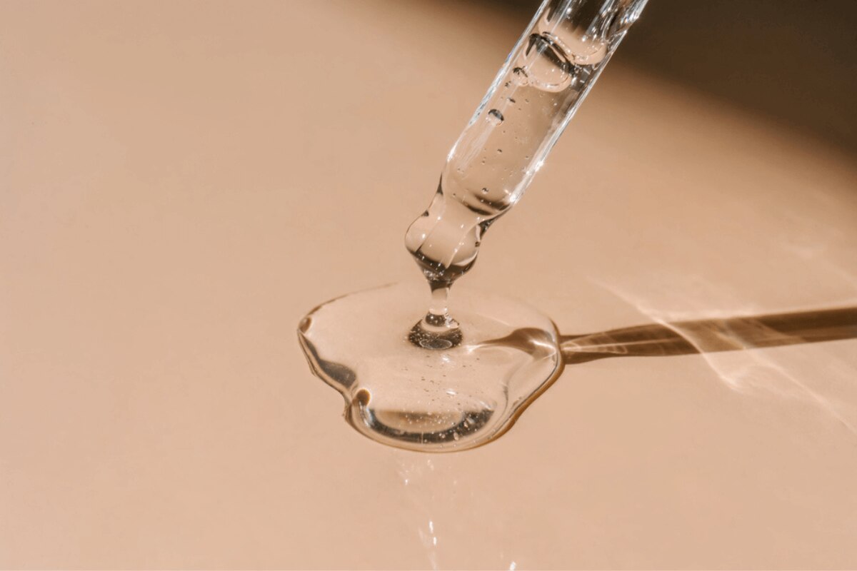 serum là gì giọt serum trong suốt nhỏ trên nền màu da 