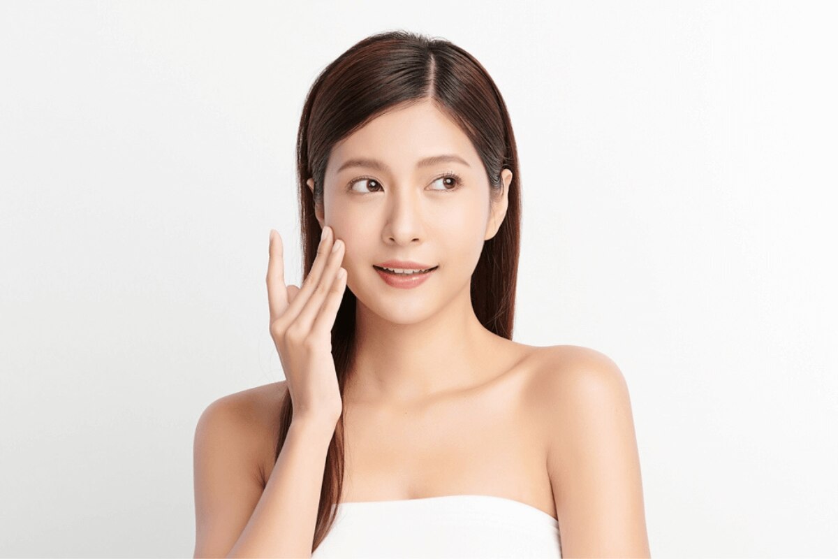 serum là gì serum có tác dụng gì cô gái mặc nửa thân tay chạm nhẹ vào má trên nền trắng