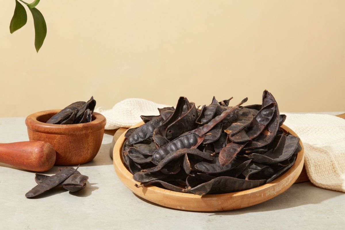 Cách trị tóc bạc sớm ở nữ bồ kết tự nhiên được bày trên đĩa tròn và đựng trong cối