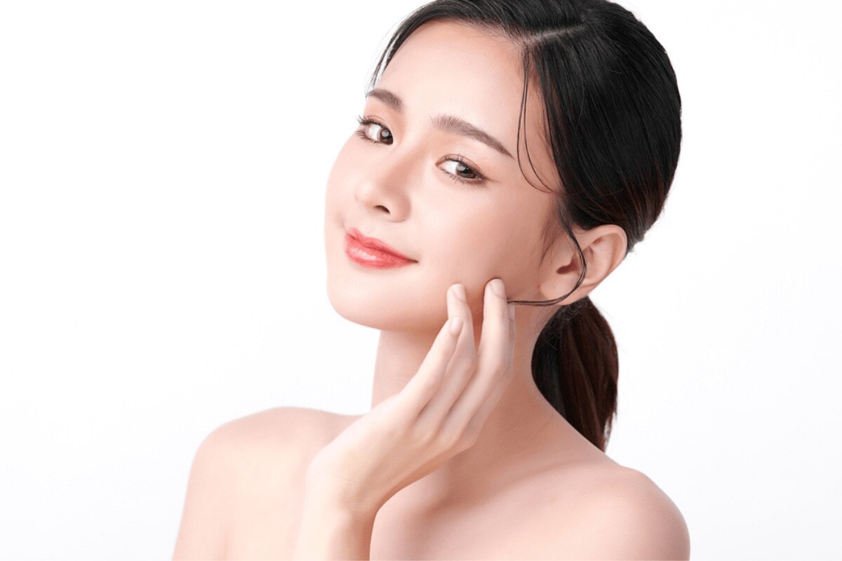 serum là gì serum có tác dụng gì dưỡng sáng da cô gái với làn da sáng hồng lấy các ngón tay chạm nhẹ vào má nhìn nghiêng