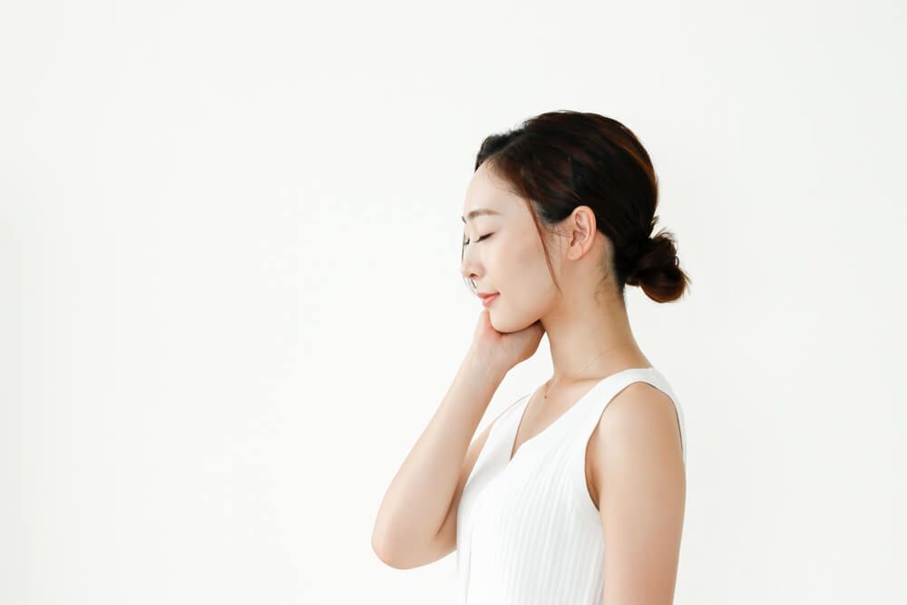 da chảy xệ do giảm cân người phụ nữ đứng nghiêng nhắm mắt tay chạm vào má bên phải