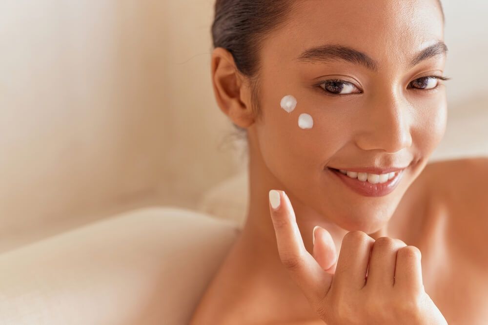 cách khắc phục da bị chảy xệ dùng mỹ phẩm cô gái thoa kem lên má