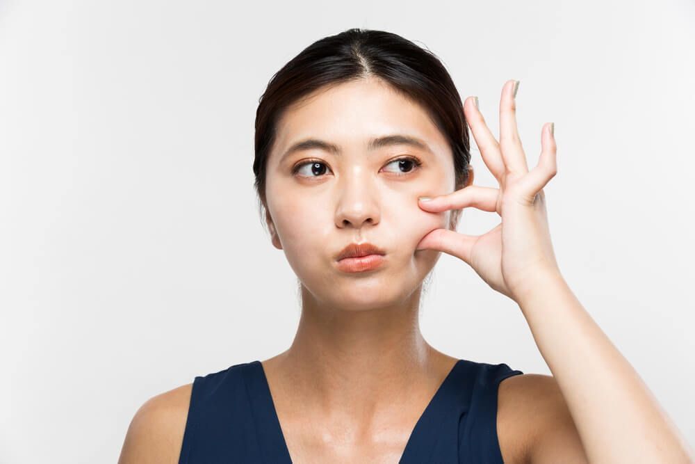 cách làm mặt thon gọn cô gái đang tự dùng tay nhéo má