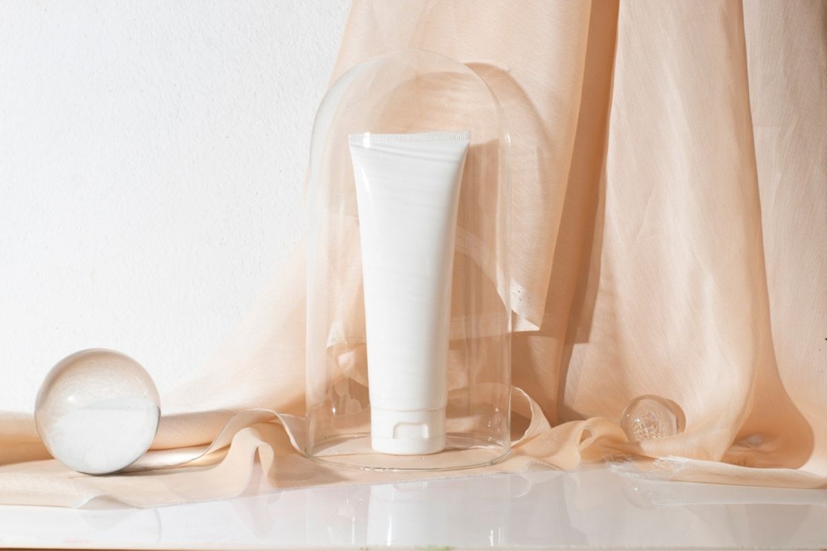 cách bôi lại kem chống nắng tuýp sản phẩm màu trắng trong lồng kính kế bên lớp vải màu da