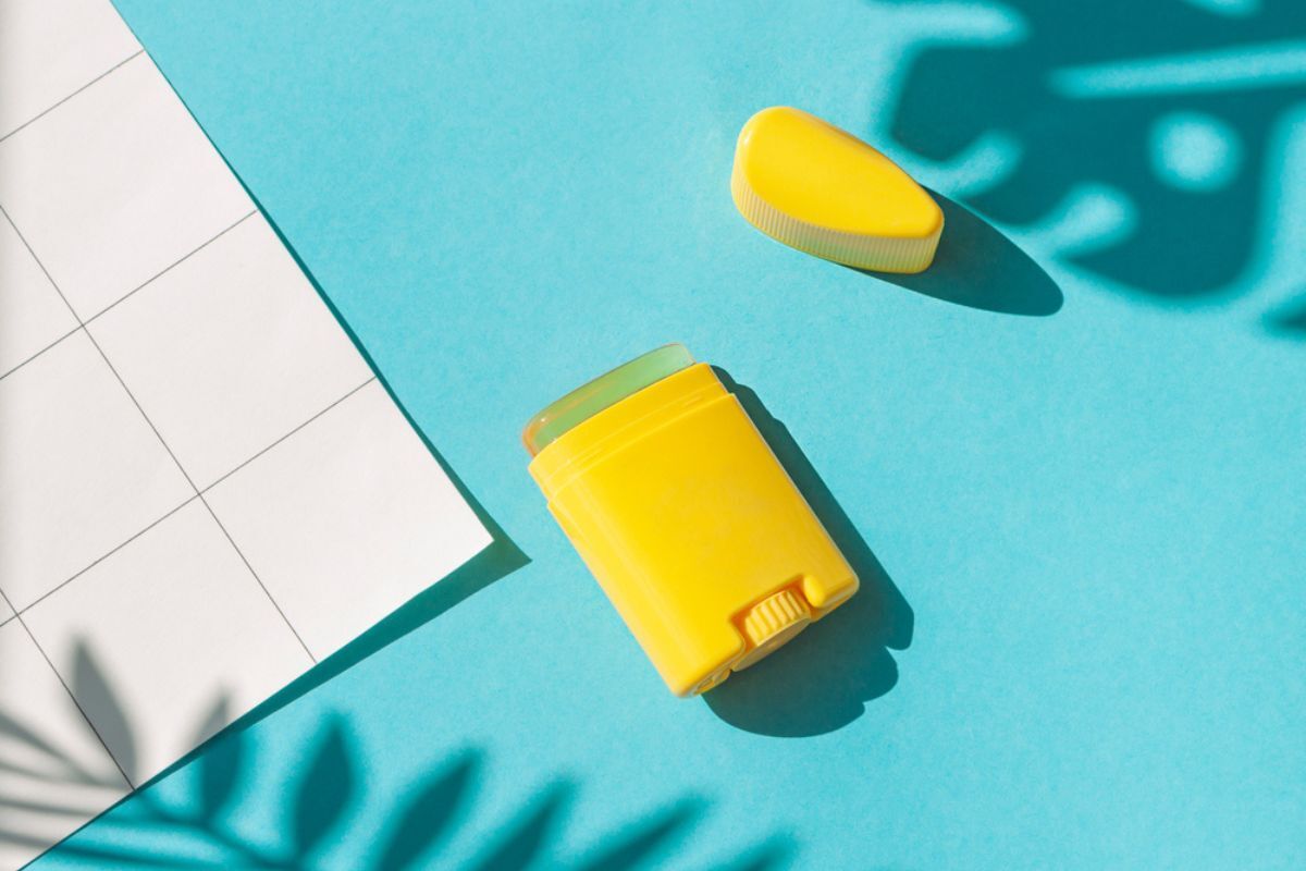 cách bôi lại kem chống nắng thỏi chống nắng màu vàng trên nền xanh và gạch ô vuông trắng sữa