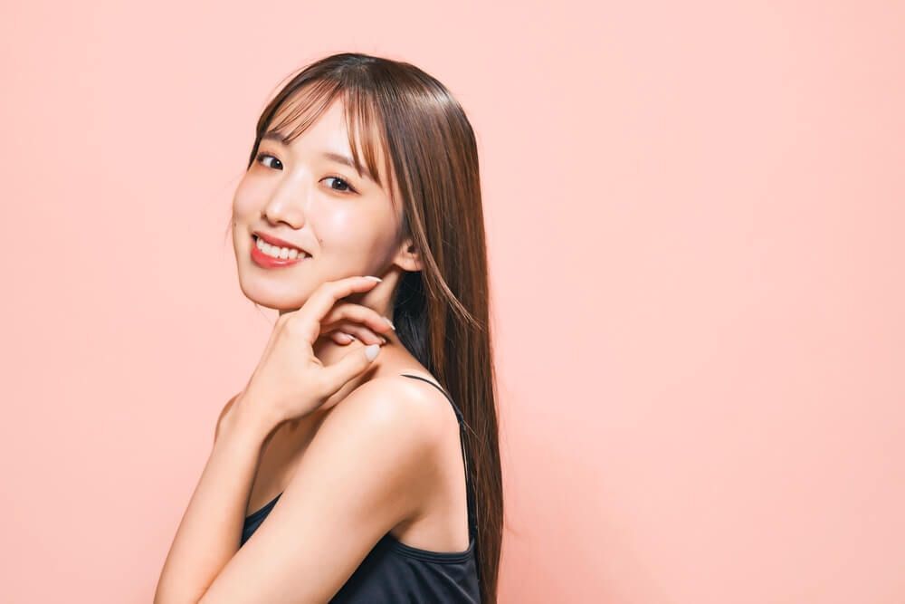 cách làm mặt thon gọn cô gái đang cười tươi và chạm tay lên cằm
