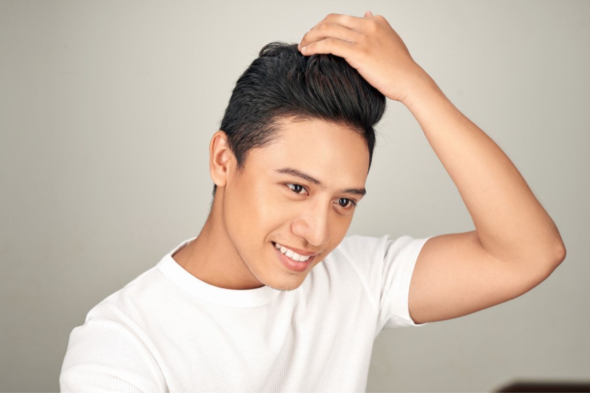 gội đầu nhiều có tốt không đàn ông nên gội đầu mấy lần 1 tuần là đủ chàng trai mặc áo thun trắng đang đưa tay lên vuốt tóc