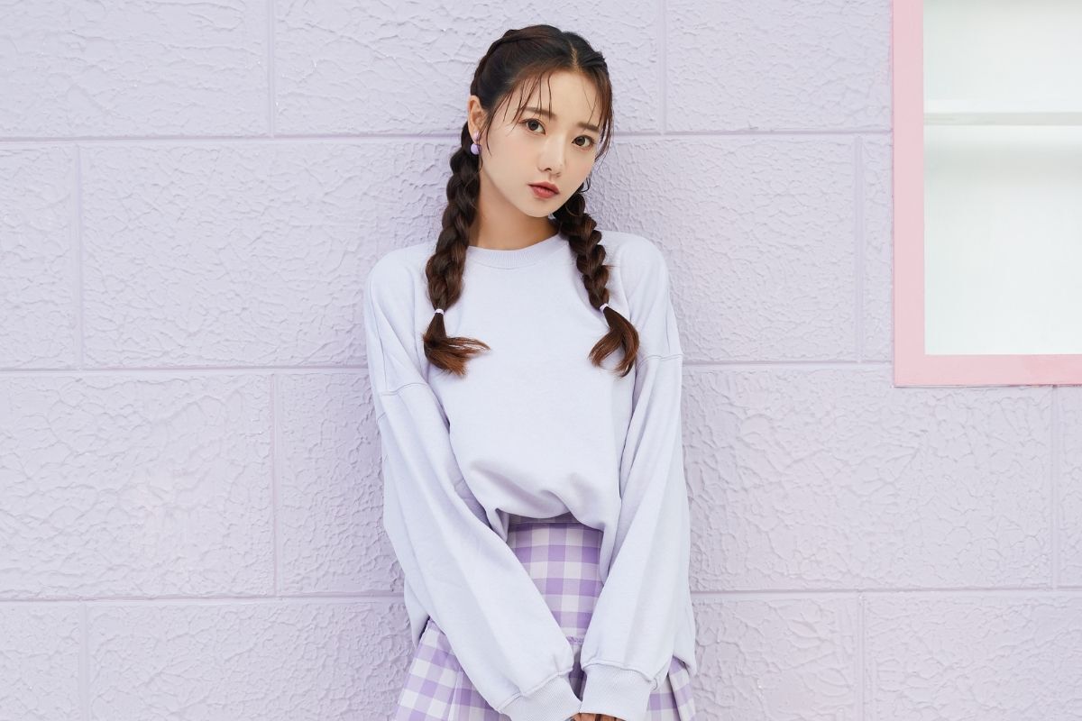 Tết tóc 2 bên cho mặt tròn cô gái mặc áo dài tay màu xanh dương chụp trên nền tường màu tím