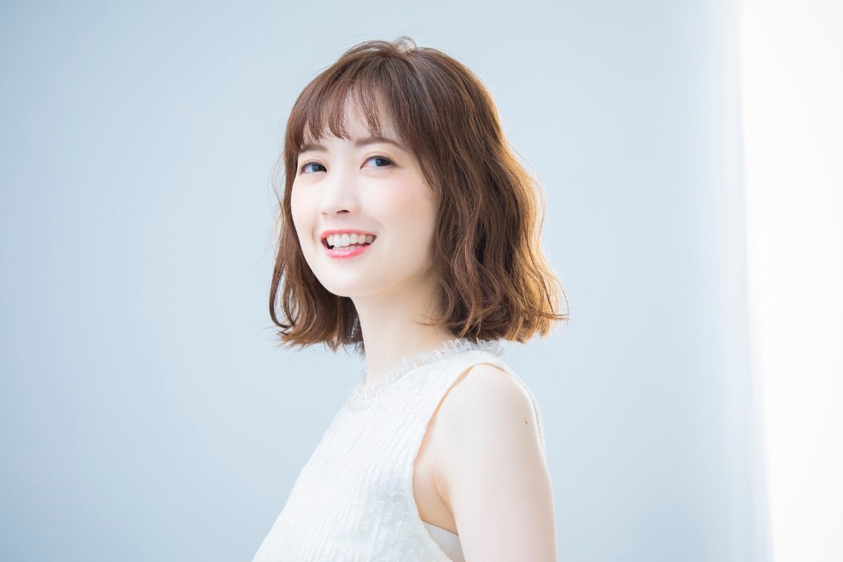 tóc ngắn nữ cá tính tóc ngắn cá tính xoăn sóng nước cô gái mỉm cười tươi nền phía sau màu trắng xám 