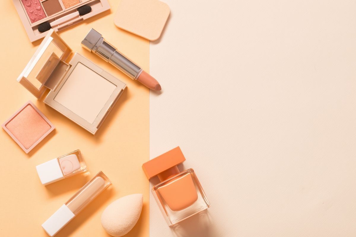 cách trang điểm tông màu cam đất các món đồ trang điểm và mỹ phẩm có vỏ màu cam nằm trên nền cam và màu da chia ra