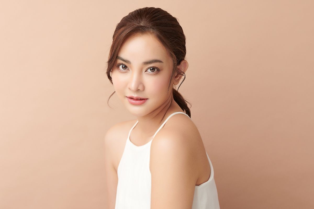 Làm hotgirl ảnh không khó với 5 mẹo này cô gái mặc áo hai dây trắng buộc tóc gọn gàng chụp trên phông nền nâu be