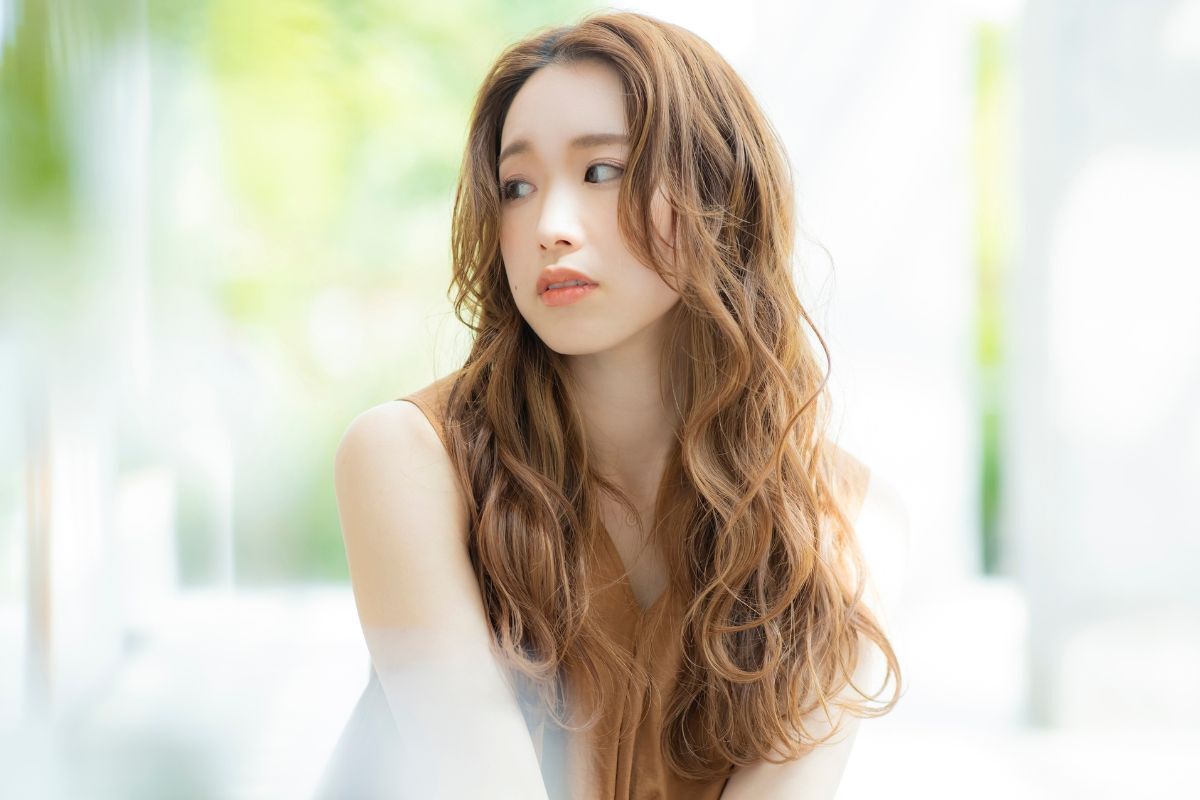 Tóc layer nữ xoăn bung cô gái nhìn sang bên trái phông nền bị làm mờ