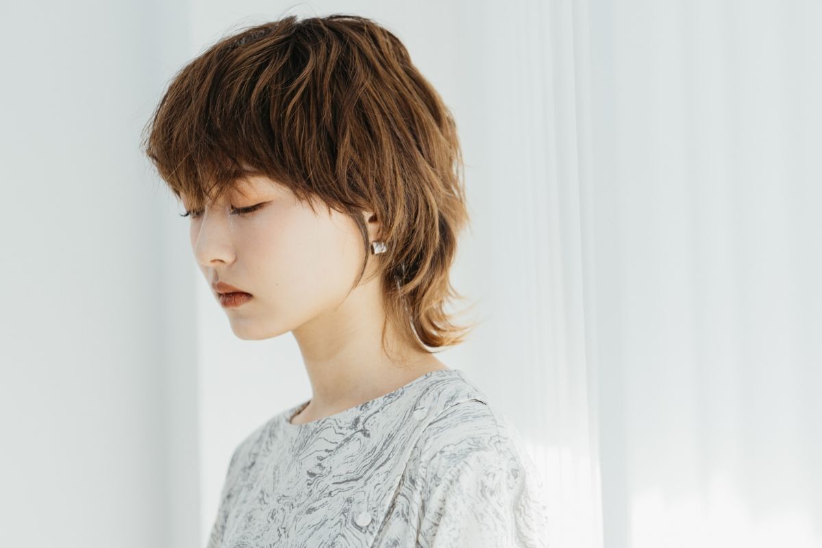 Tóc layer mullet dành cho nữ cô gái đang cúi xuống nhìn mặc áo hoa tiết 