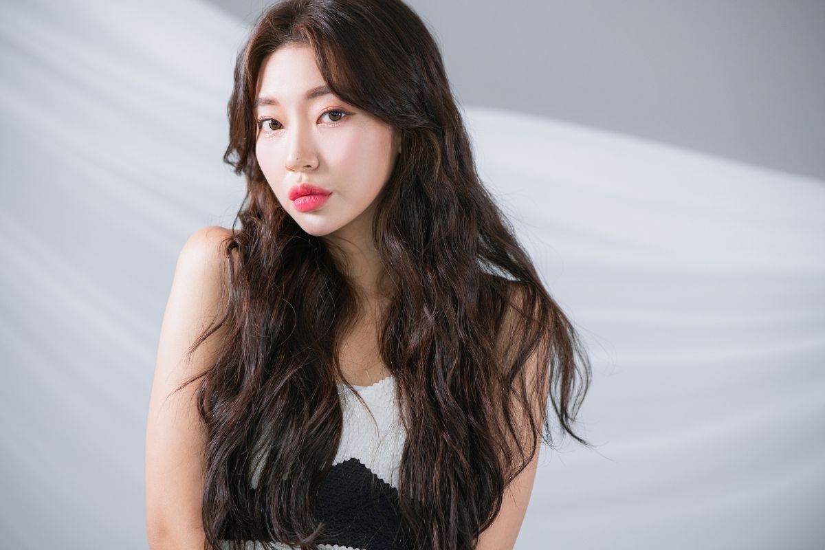 Tóc layer nữ xoăn sóng lơi cô gái mặc áo màu đen và trắng chụp trên nền tường xám