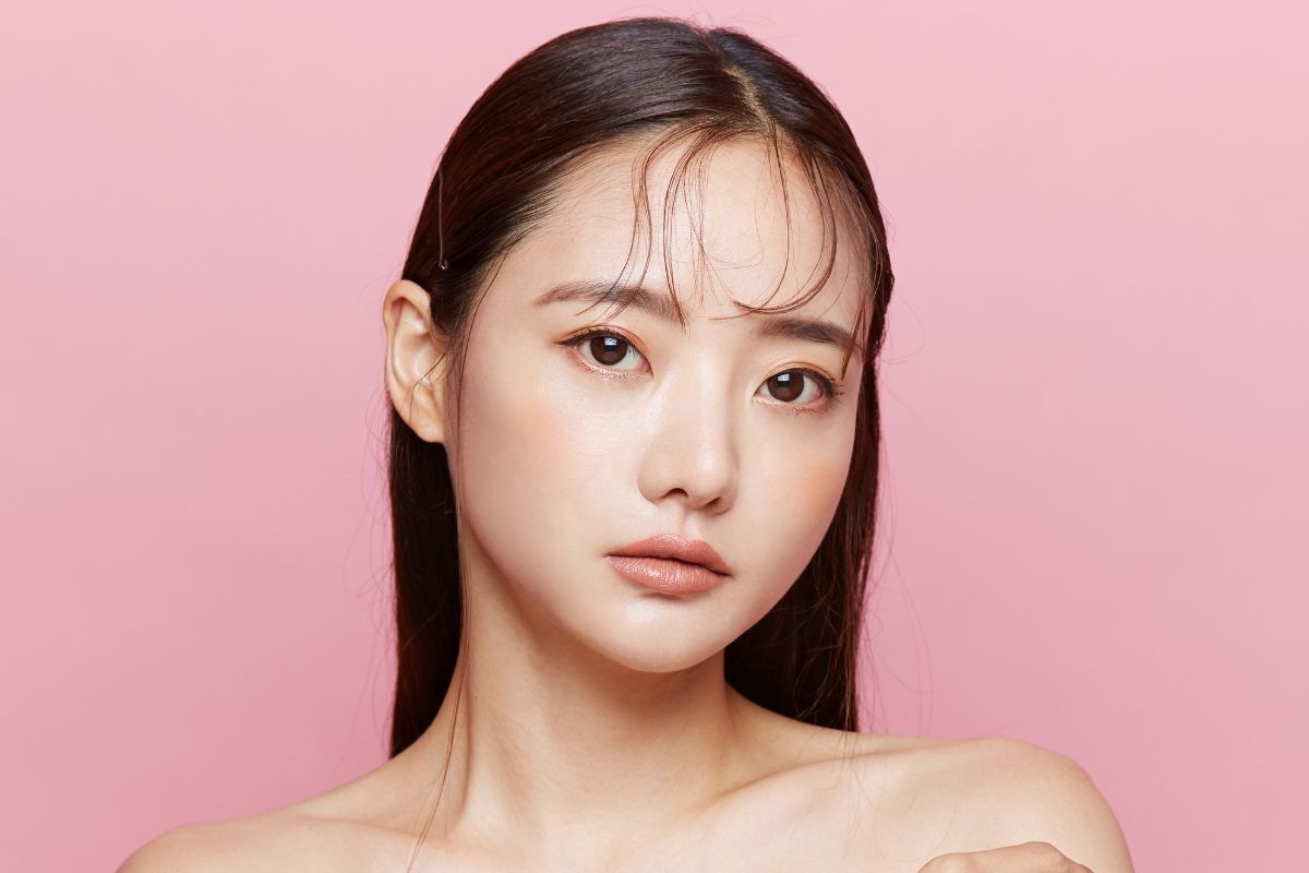 Mẫu lông mày ngang đẹp tự nhiên cô gái trang điểm đơn giản xoã tóc với vài sợi tóc mái phía trước trán chụp ảnh trên nền hồng