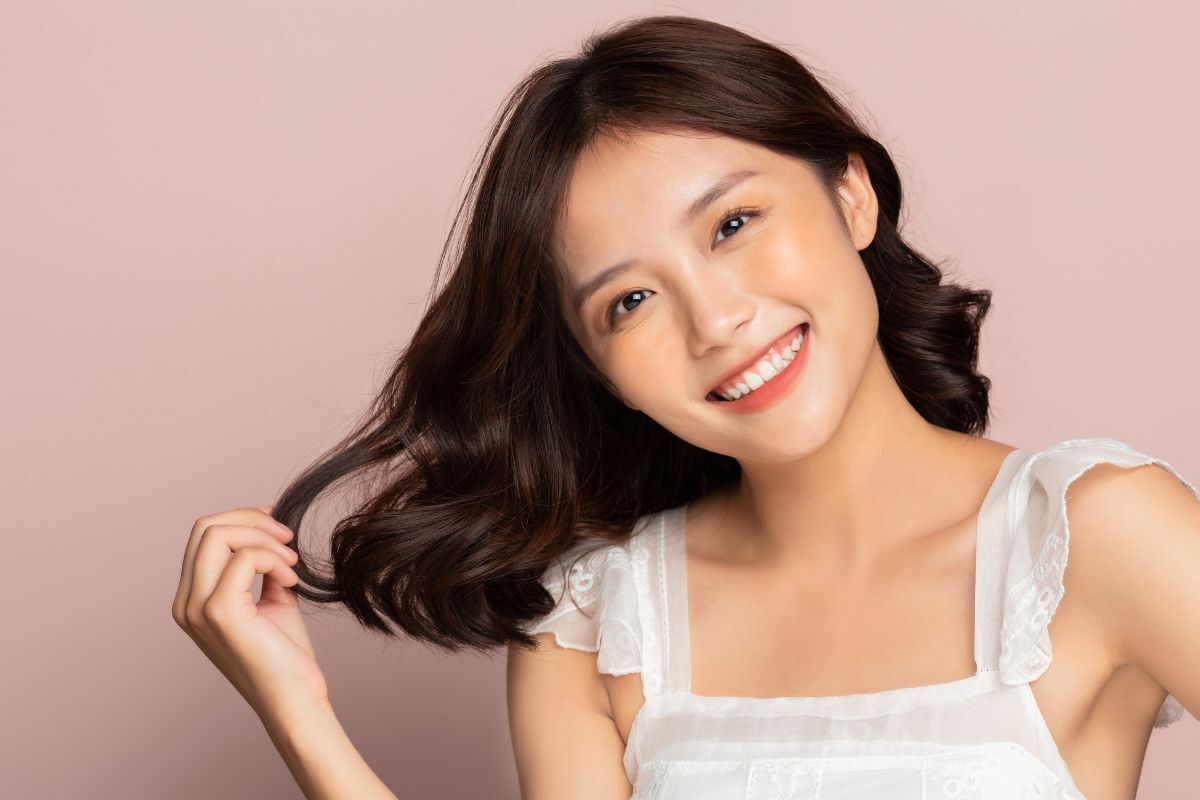 Dáng lông mày ngang cho mặt tròn cô gái cười tươi một tay đang chạm vào tóc