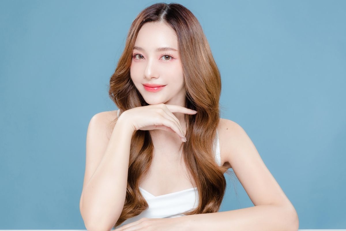 Son màu đỏ cam cô gái mỉm cười chống tay trên nền xanh dương