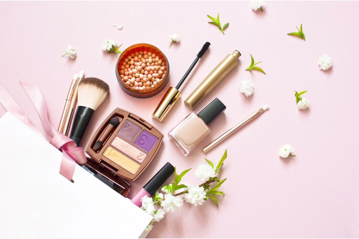 makeup nhẹ nhàng đồ trang điểm có phấn nền má hồng dạng viên mascara son nằm trong hộp trắng trên nền hồng