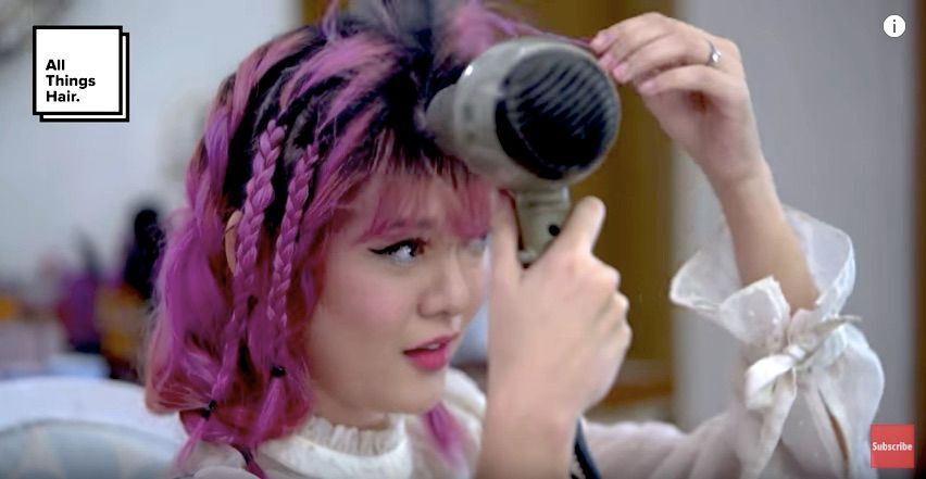 Sonia Eryka dengan warna rambut pink sedang menggunakan hair dryer pada bagian atas rambut