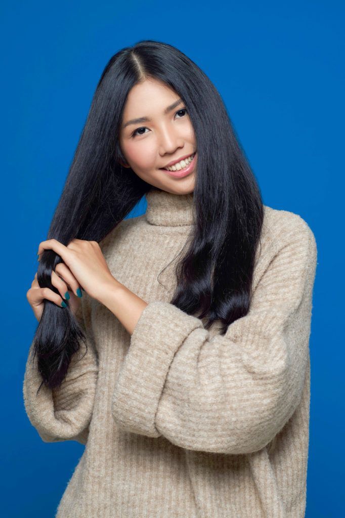 Wanita asia dengan rambut hitam panjang menyisir rambut dengan jari – cara mengatasi rambut kusut.