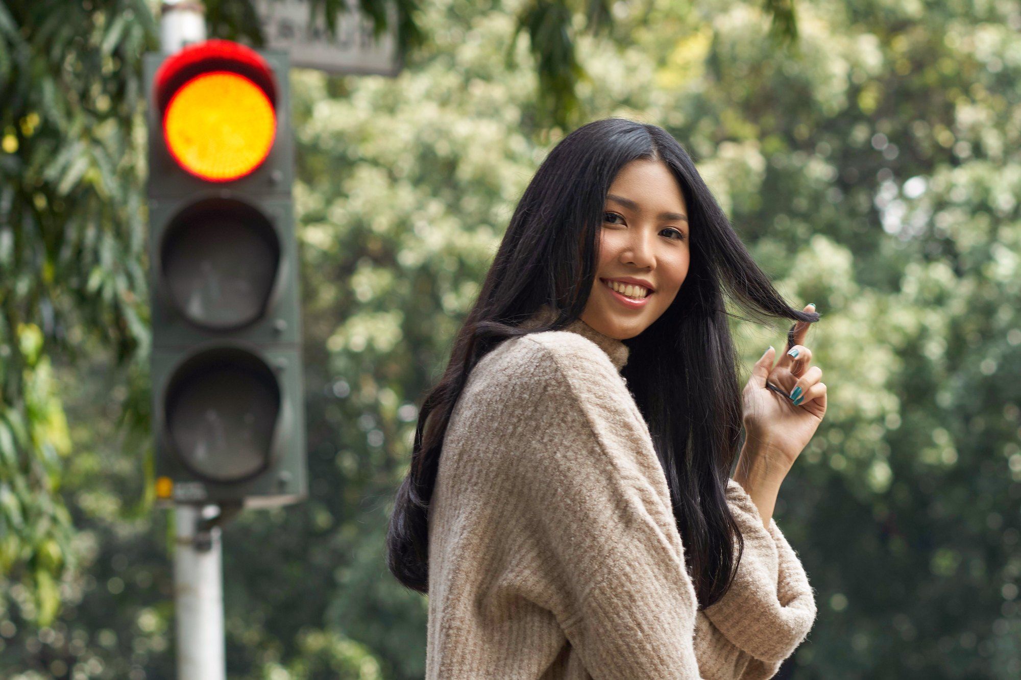 Wanita asia dengan rambut panjang hitam menata rambut untuk mengatasi rambut kusut.
