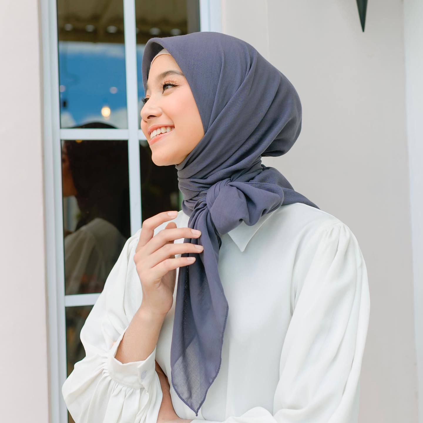 Wanita Indonesia mengenakan hijab bahan paris warna abu-abu tua.
