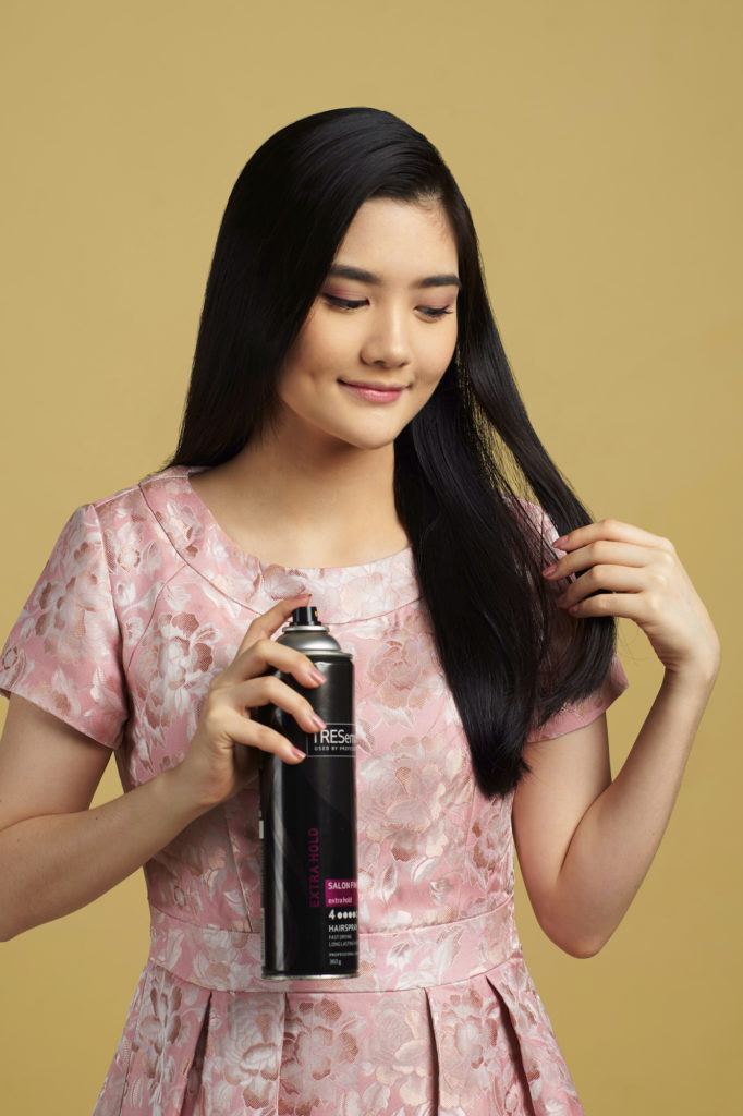 Wanita asia dengan model rambut hitam panjang menyemprotkan hairspray - side part sleek low bun