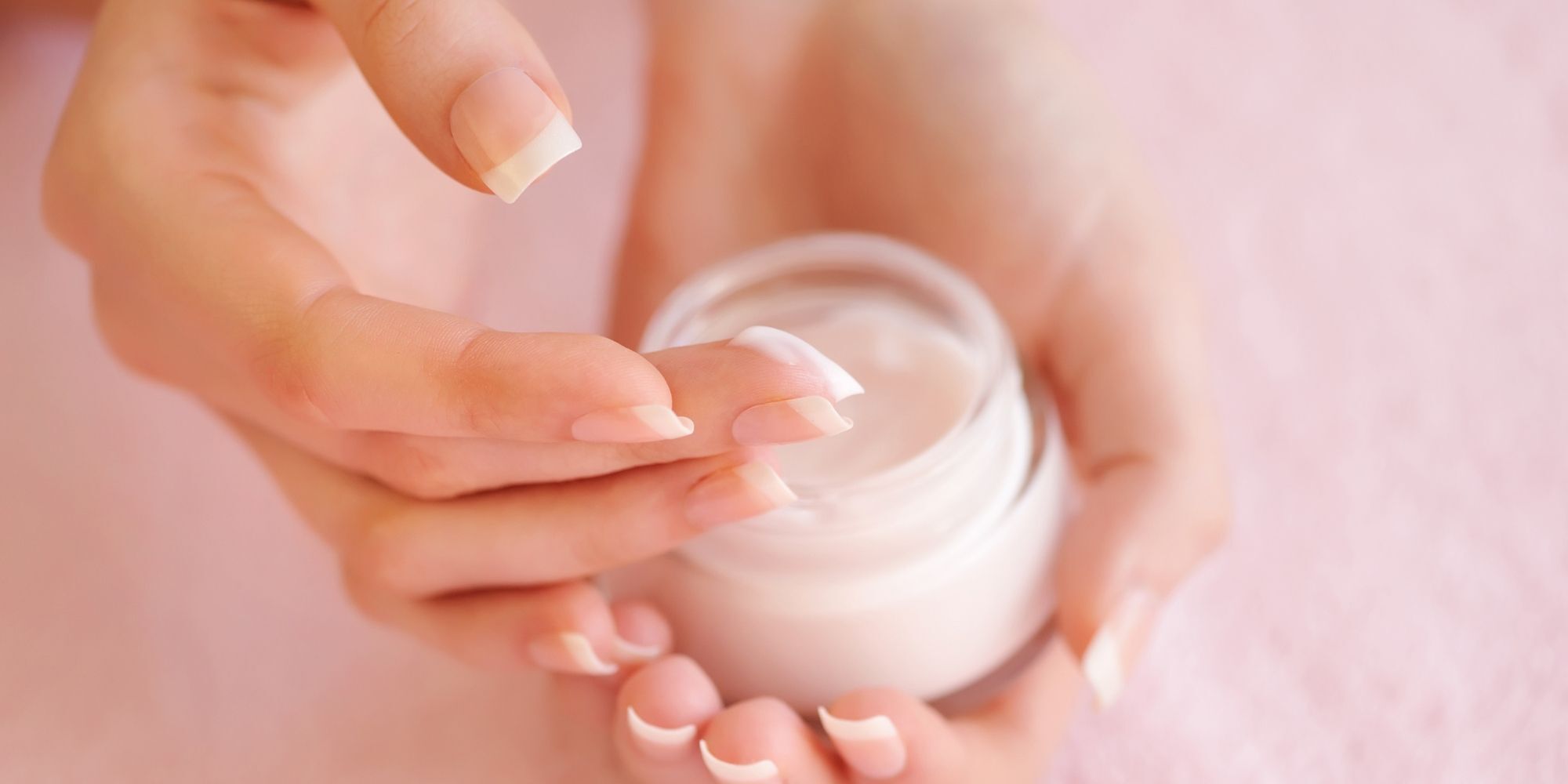 wanita sedang mengambil krim wajah dari kemasan