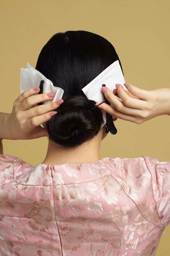 Wanita asia dengan model rambut hitam panjang membuat cepol - side part sleek low bun