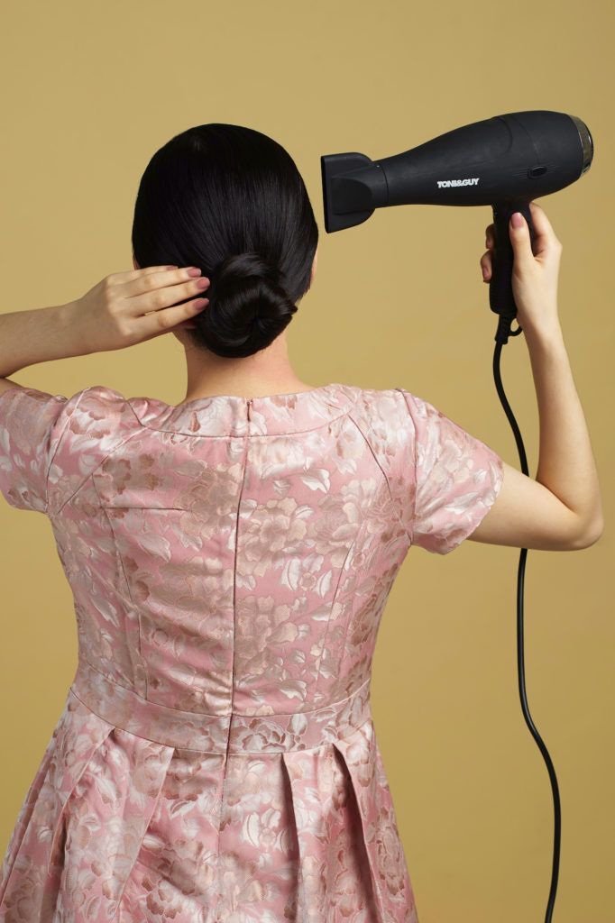 Wanita asia dengan model rambut hitam panjang menyemprotkan hairspray - side part sleek low bun