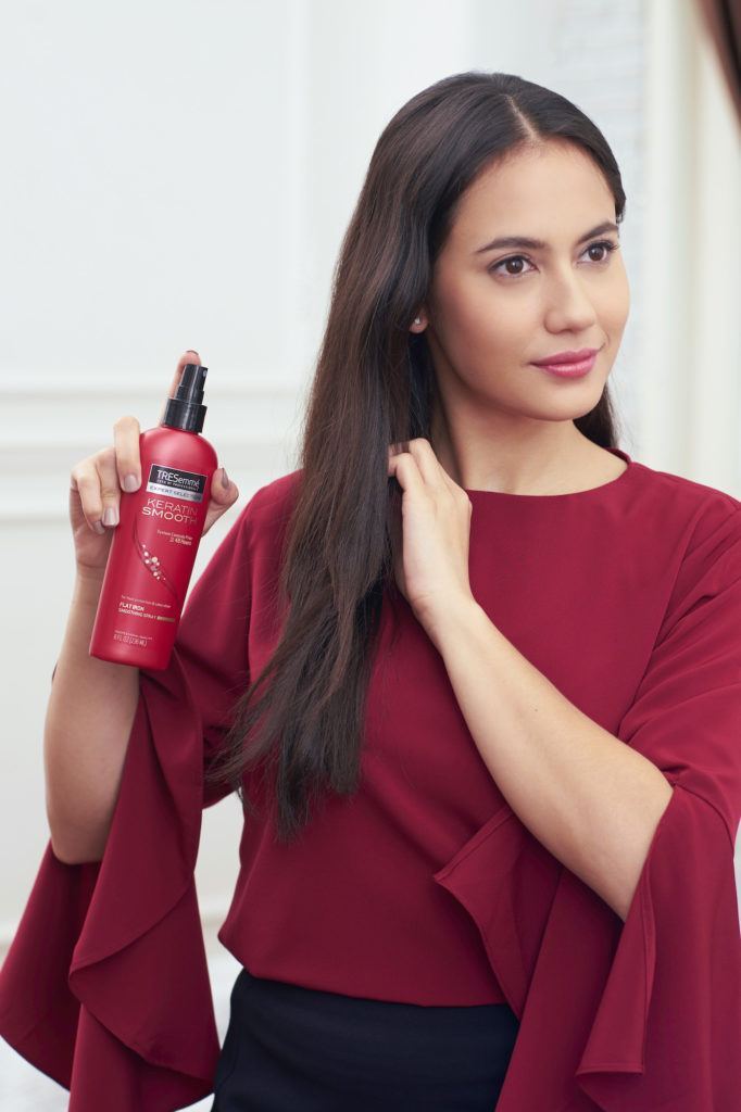 Pevita Pearce menyemprotkan rambut heat protection pada rambut menggunakan baju merah